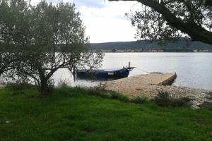 a small boat on the shore of a lake at Secluded fisherman's cottage Cove Komornik, Pasman - 14801 in Pašman +2 photos
