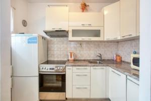 uma cozinha com armários brancos e um frigorífico branco em Apartments by the sea Grebastica, Sibenik - 482 em Grebaštica
