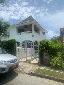 a white house with a fence and a car parked in front at Casa campestre Hacienda estancia, en Melgar con piscina privada in Melgar
