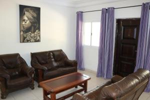 una sala de estar con muebles de cuero y cortinas moradas. en The Rink Apartment's, en Sukuta