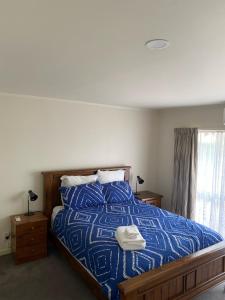 a bedroom with a large bed with a blue comforter at The Gardens' Treasure in Auckland
