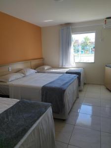 um quarto de hotel com três camas e uma janela em JL Temporadas - Quarto Portobello Park Hotel em Porto Seguro