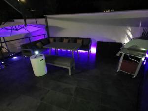 Cette chambre dispose d'un canapé et d'une table avec des lumières violettes. dans l'établissement Maison spa sauna, à Morangis