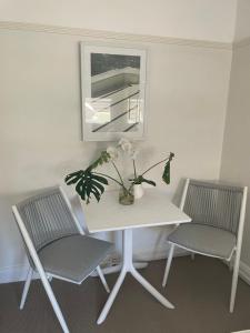 une table blanche avec deux chaises et un vase avec des fleurs dans l'établissement Manly Retreat, à Sydney
