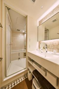 a bathroom with a sink and a shower and a mirror at Hotel TORACO konohana in Osaka