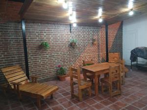 Habitación con mesas y sillas de madera y pared de ladrillo. en Departamento Juana-Franch en Salta