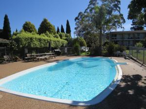 a large blue pool with a picnic table and trees at Golfview Lodge in Bowral