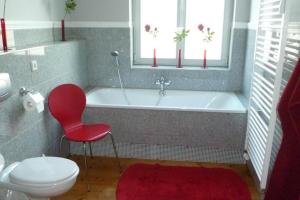 e bagno con sedia rossa e vasca. di Ferienwohnungen Villa Haniel Julius a Dresda Altre 29 foto
