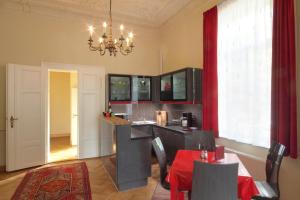 een keuken met een tafel en stoelen en een kroonluchter bij Ferienwohnungen Villa Haniel Hugo in Dresden