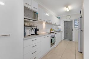 a white kitchen with white cabinets and appliances at Longbeach Unit 12 in Gold Coast