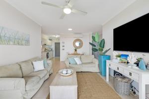 a living room with white furniture and a flat screen tv at Longbeach Unit 12 in Gold Coast