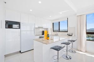 a kitchen with white appliances and a counter with stools at Royal Palms 24 F in Gold Coast