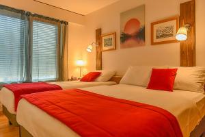 two beds with red pillows in a room at Hotel des Alpes Bulle center in Bulle