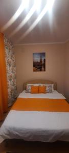1 dormitorio con 1 cama grande con sábanas de color naranja en 2ком квартира у Набережной в Астане en Astaná