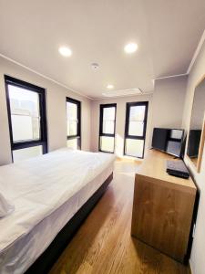 Schlafzimmer mit einem großen weißen Bett und Fenstern in der Unterkunft J.Hill House in Seoul