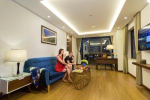 a man and woman sitting on a couch in a living room at Pavilion Hotel Da Nang in Danang
