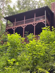 uma cabana de madeira com um deque nas árvores em Alpenhaus Cabins Real Log Home in Helen Ga Mountains with hot tub and balconies em Sautee Nacoochee