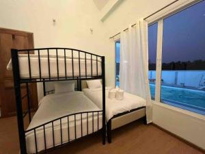 a bedroom with two bunk beds next to a window at The PaVillu de Pool Villas in Samut Songkhram