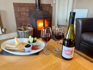 a table with two glasses of wine and a plate of food at Glenachulish Bay with Hot Tub in Glencoe +13 photos