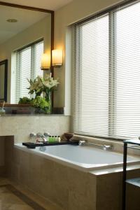 a large bath tub in a bathroom with a mirror at Bumi Surabaya City Resort in Surabaya