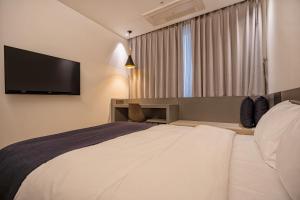 清州市Gloucester Hotel Cheongju的一间配有床和平板电视的酒店房间