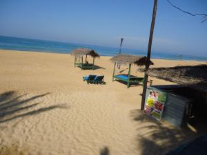 una playa con sillas y sombrillas y el océano en Whitepearl Beach, en Hikkaduwa