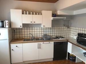 Elle comprend une petite cuisine avec des placards blancs et un évier. dans l'établissement Maison Bretignolles-sur-Mer, 3 pièces, 6 personnes - FR-1-231-188, à Bretignolles-sur-Mer