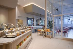 um restaurante com uma linha de buffet com mesas e cadeiras em Ibis Styles Jakarta Mangga Dua Square em Jakarta