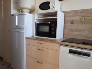 eine Küche mit einer Mikrowelle und einem Kühlschrank in der Unterkunft Notre-Dame-de-Monts (85) - Appartement de vacances 55m² environ - 5 personnes - FR-1-540-147 in Notre-Dame-de-Monts + 13 Fotos