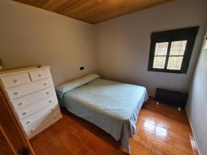 a bedroom with a bed and a dresser and a window at Eira Vella Bueu in Bueu