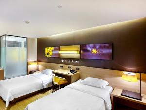 a hotel room with two beds and a tv on the wall at 7Days Premium Guilin central plaza in Guilin