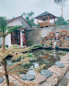 a pond in front of a house with a building at Madinna Villa Dieng in Dieng