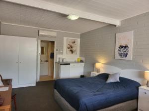 a bedroom with a blue bed and a kitchen at Peterborough Motel in Peterborough