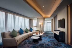 a living room with a couch and a tv at Primus Hotel Shanghai Hongqiao in Shanghai