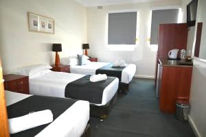 Habitación de hotel con 2 camas y escritorio en Knickerbocker Hotel en Bathurst