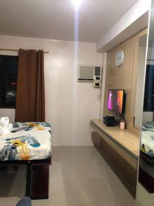 een kamer met een bed en een bureau met een televisie bij Ellie’s Place in Cebu City