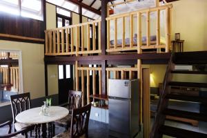 Cette chambre comprend des lits superposés, une table et des chaises. dans l'établissement Bamboo Cottage Langkawi, à Pantai Cenang