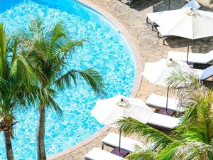 an overhead view of a swimming pool with umbrellas and palm trees at Hotel Nikko Alivila in Yomitan