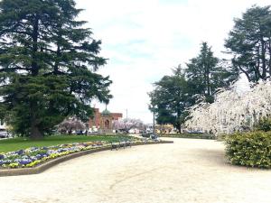 a park with benches and flowers and trees and a building at Knickerbocker Hotel in Bathurst