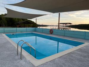 a large swimming pool with an umbrella over it at TANJUNG GROVE VILLAS in Menumbok