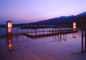 een pier met 's nachts licht in het water bij Kohan No Yado Yoshidaya in Sado