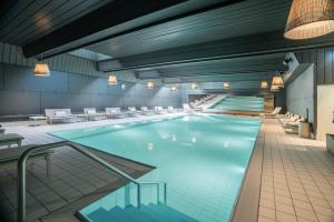 a large swimming pool with white chairs in a building at Haus Whymper in Zermatt