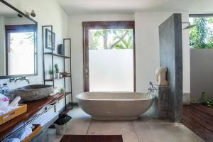 a bathroom with a large tub and a sink at Kamehameha Luxury Villa in Seminyak