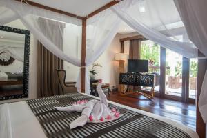 a bedroom with a bed and a mirror at Kamehameha Luxury Villa in Seminyak