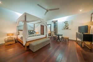 a bedroom with a canopy bed and a desk and a television at Kamehameha Luxury Villa in Seminyak