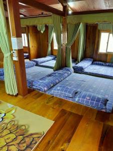 a room with three beds in it with wooden floors at Homestay duy mạnh gần suối nước khoáng nóng trạm tấu in Cham Ta Lao