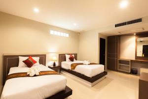 a hotel room with two beds and a television at Pranee Home Phang-nga in Ban Khaek