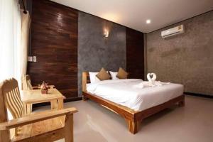 a bedroom with a large bed and a wooden wall at โรงแรมบ้านมะกรูด Baan Ma Grood Hotel in Phayao