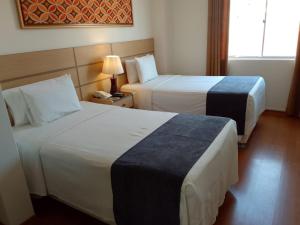 a hotel room with two beds and a lamp at Xima Central Tacna in Tacna