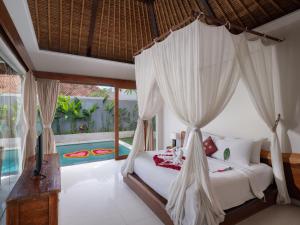 a bedroom with a canopy bed and a pool at Avery Le Nixsun Villas Uluwatu by Waringin Hospitality in Jimbaran